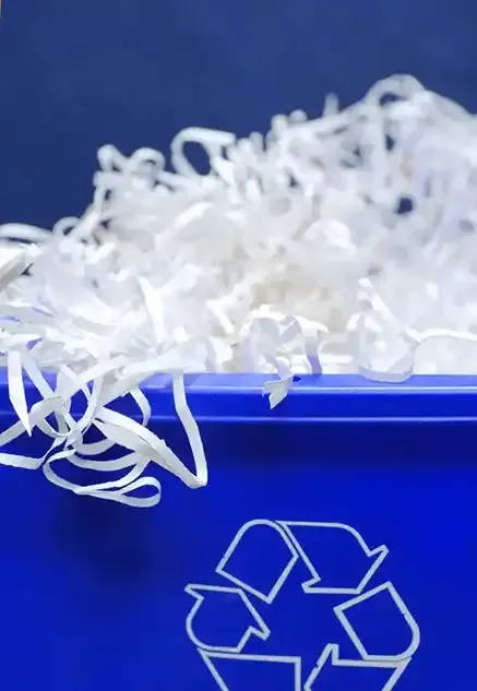 shredding documents in a recycling bin